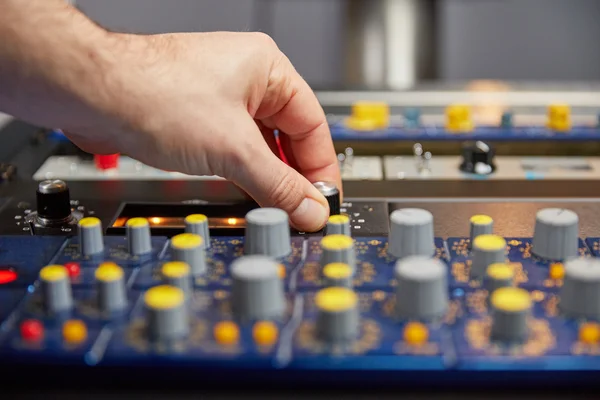 Hand of audio engineer turning the knobs on an audio mixer