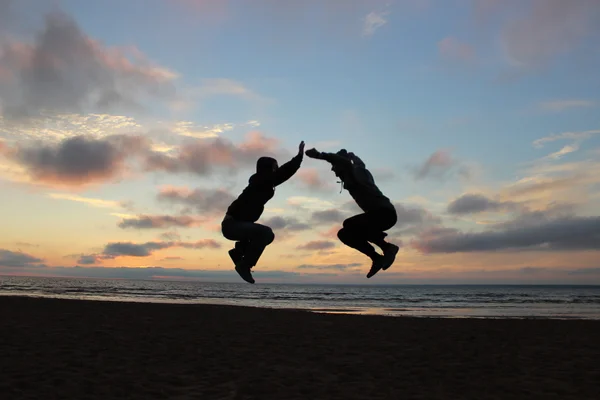 Two man jump hight in front of sea sunset
