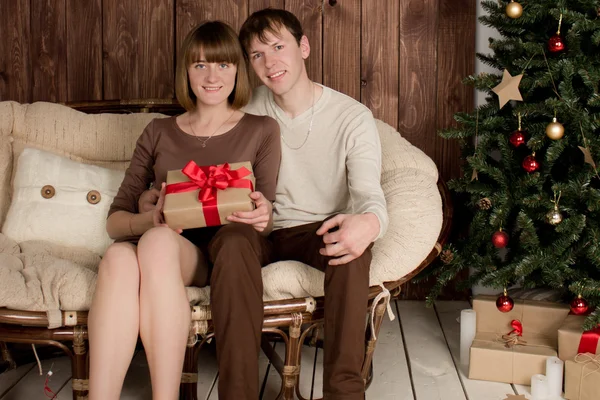 Young man and woman sits near christmas tree