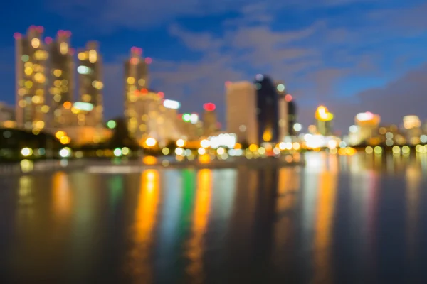 Water reflection, blurred lights night view city office building