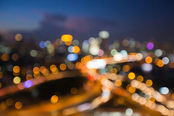 Blurred bokeh light during twilight, city intersection highway with office building background