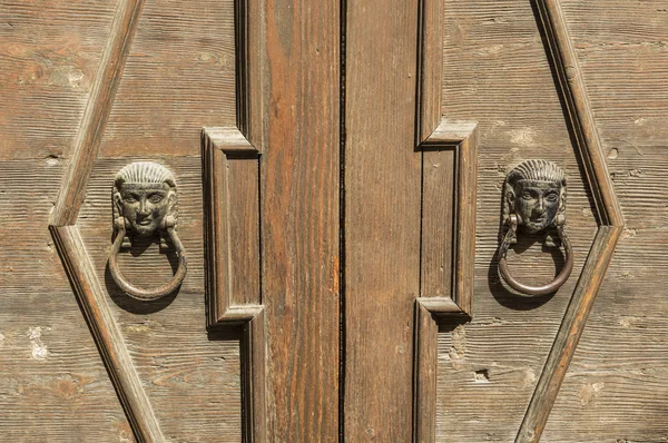 Old wooden door with knocker in bronze