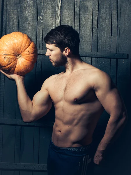 Muscular guy with pumpkin