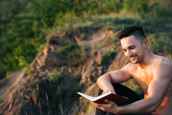 Smiling muscular man with book outdoor