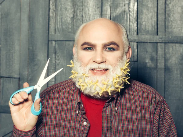 Old man with flowers in beard and scissors