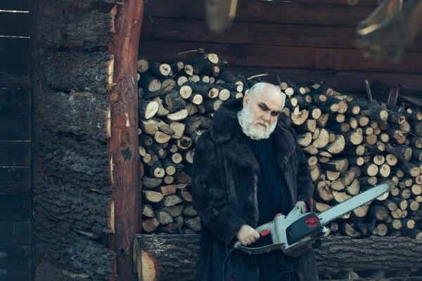 Old bearded man with chainsaw