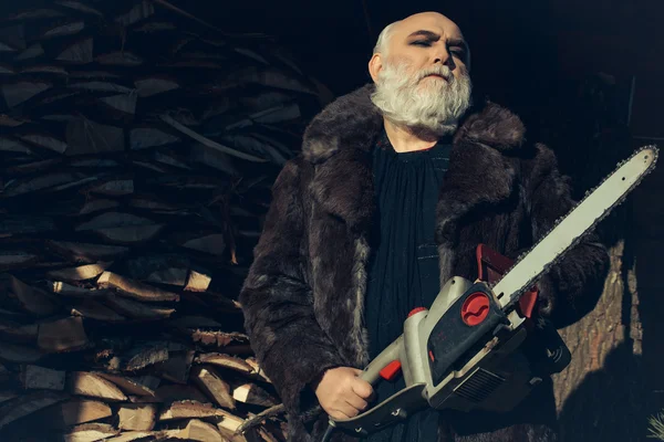 Old bearded man with chainsaw