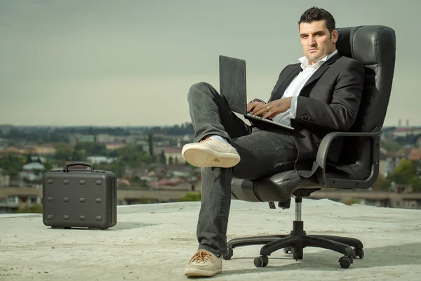 Businessman with laptop on chair outdoor