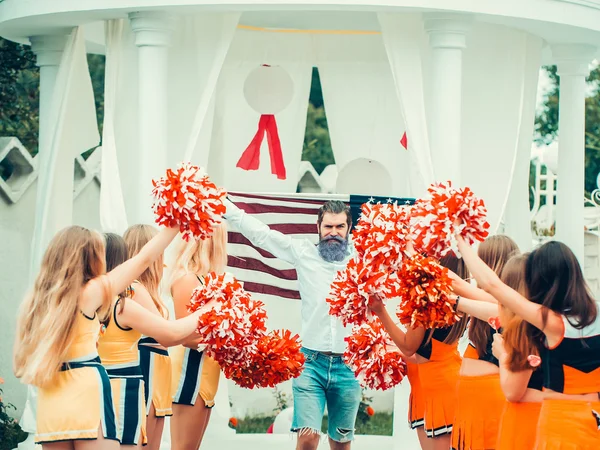 Man with american flag and cheerleader team