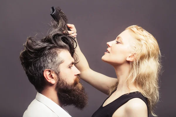 Blonde hairdresser combing bearded man