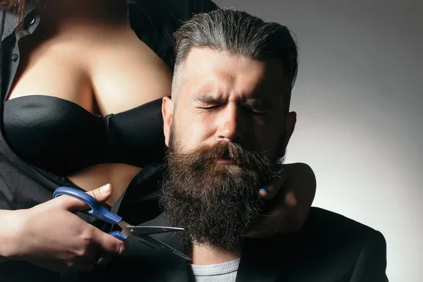 Sexy woman cutting male beard