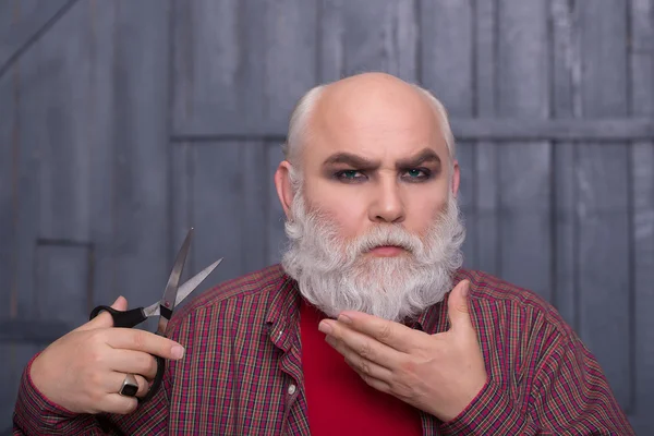 Old man cutting beard with scissors