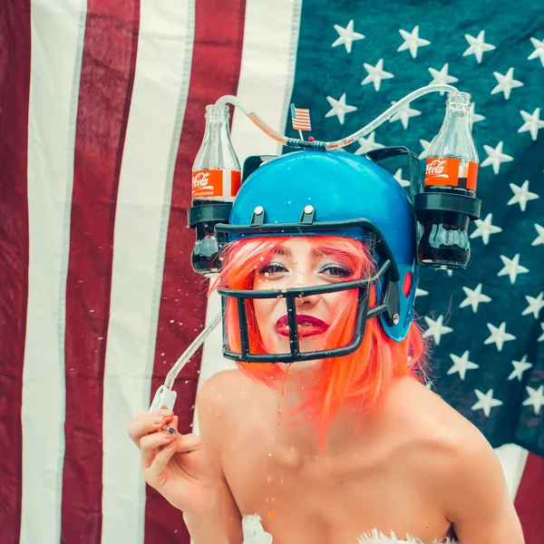 Woman in american football drink helmet