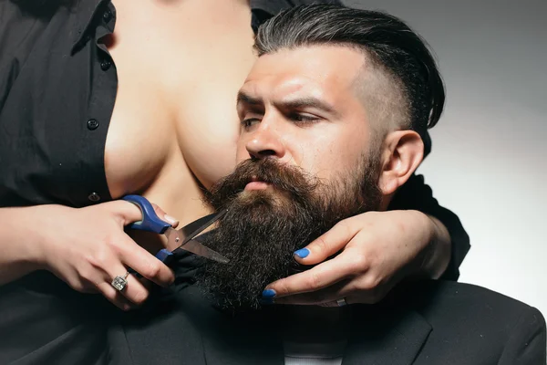 Bare woman cutting male beard