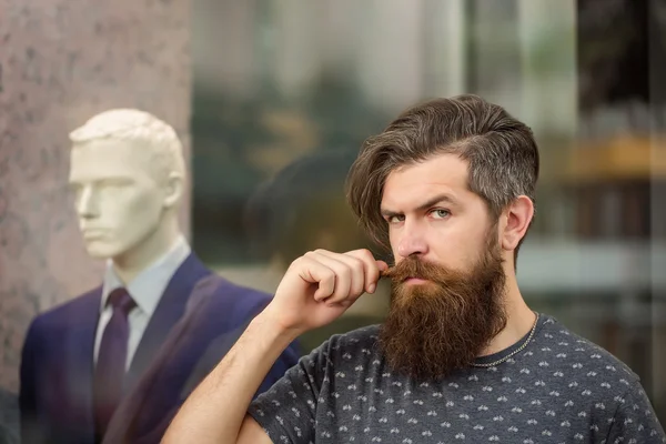 Bearded man near showcase with dummy