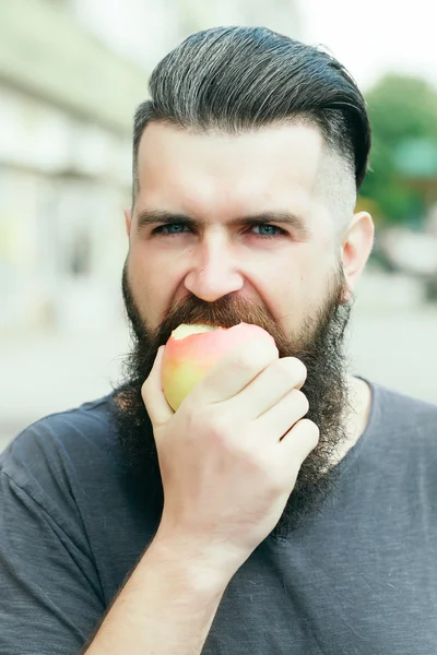 Bearded man eating apple
