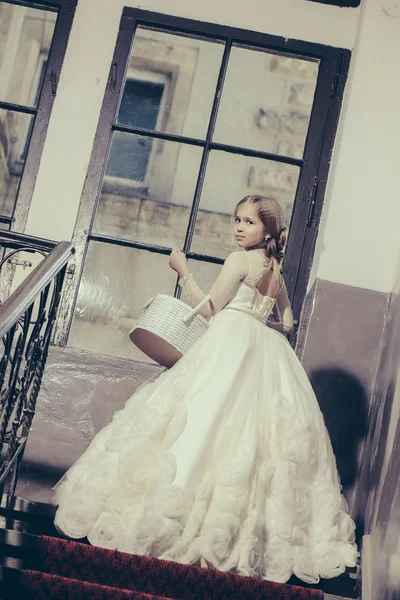 Small girl in white dress near big window