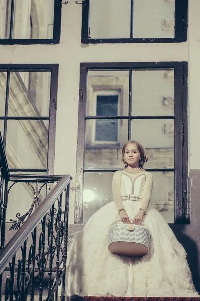 Small girl in white dress near big window