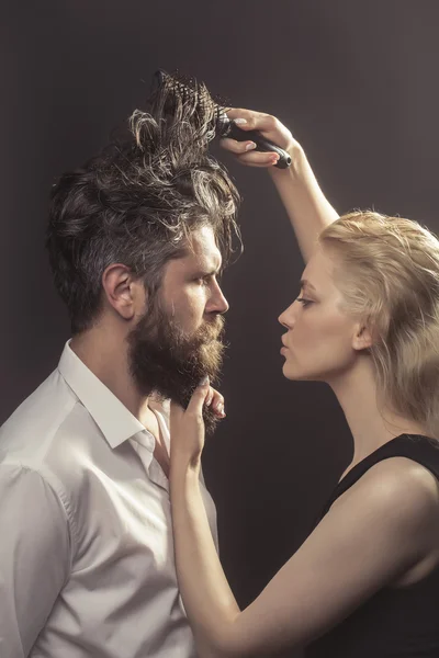 Blonde hairdresser combing bearded man