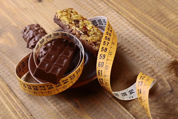 Appetizing chocolate bars and peanut brittle with a measuring tape