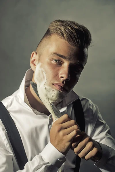 Young man shaving with knife
