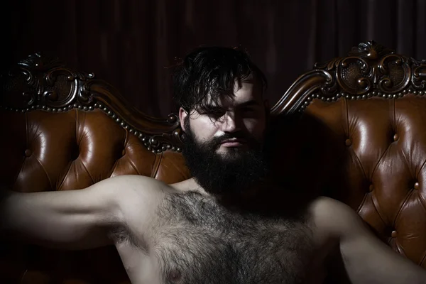 Bearded naked man on couch