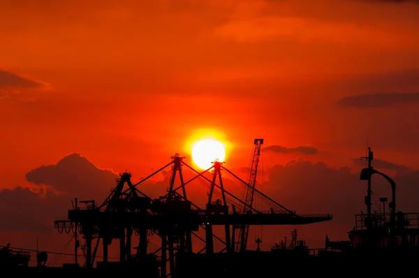Silhouette of an Industrial Dock Crane Unloading at Sunset. Izmi