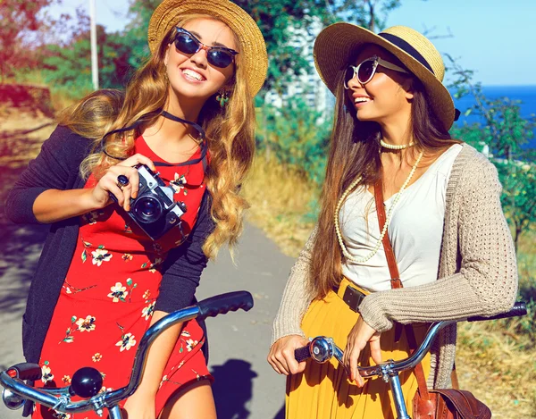 Two hipster girls walking with retro bicycles