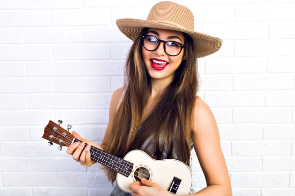 Hipster girl playing on small guitar