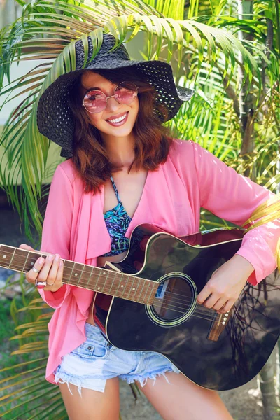 Woman posing at garden playing guitar