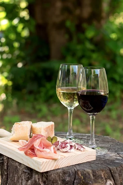 Red and white wine in a glass with sausage and ham