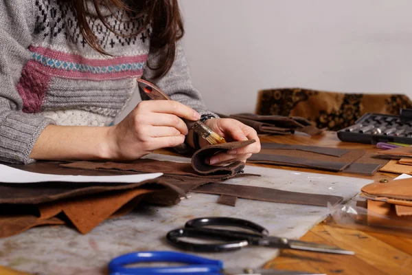 Girl makes leather purse.