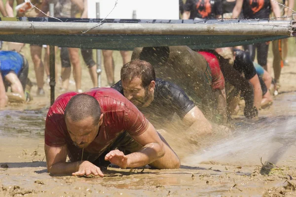 People passing  under the wires during the Inferno Run Mud Race