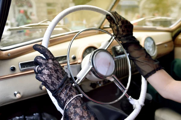 Women\'s hands in transparent gloves on the steering wheel of ret