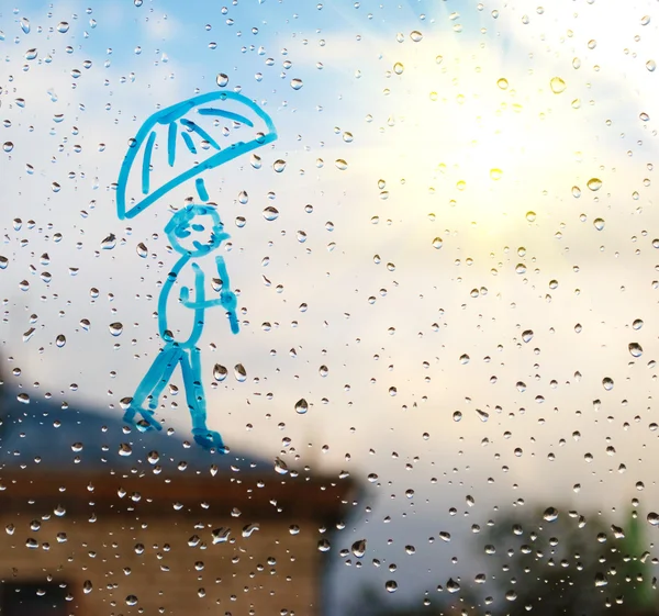 Picture of man with an umbrella on a window in the drops of rain