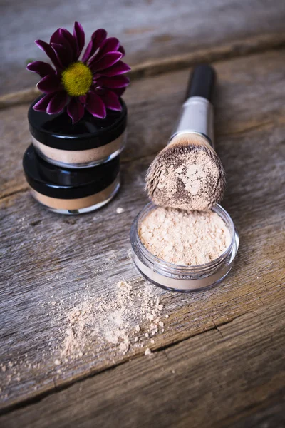 Mineral powder of different colors with a brush for make-up on wooden background