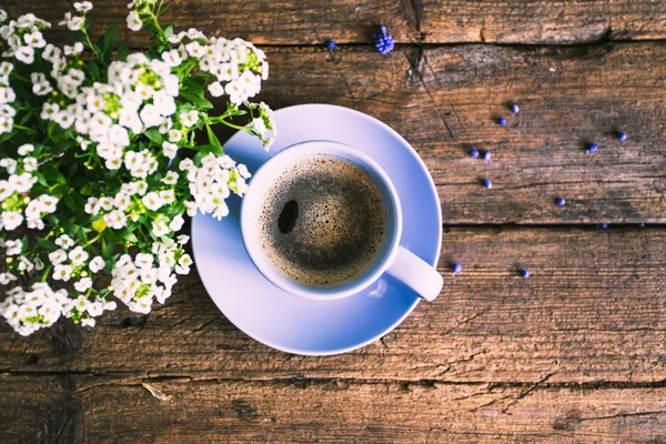 White flowers with a cup of coffee on the old wooden background