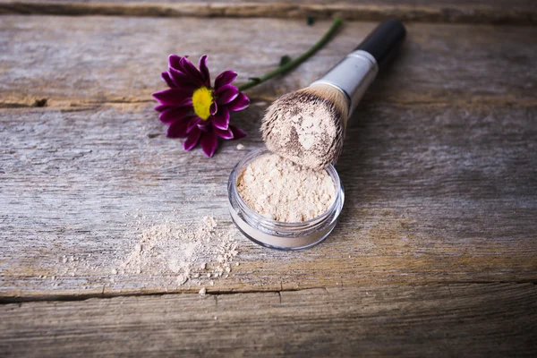Mineral powder of different colors with a brush for make-up on wooden background