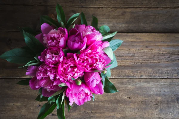 Fresh pink peonies on a wooden background