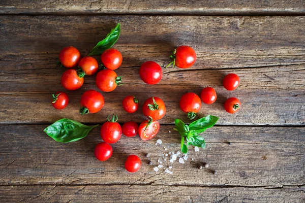 Fresh grape tomatoes with basil and coarse salt for use as cooking ingredients