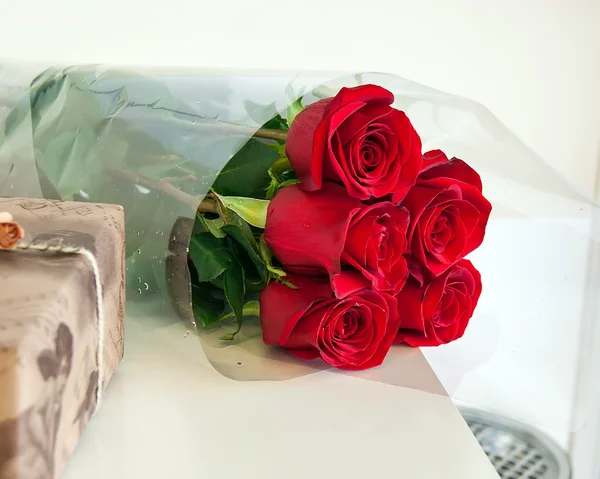 Gift box and bouquet of roses on white background