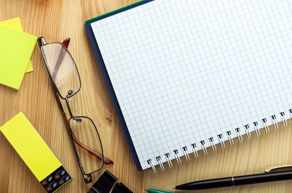 Overhead of open notebook with pen and glasses on a desk
