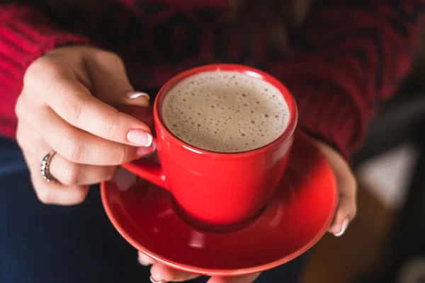 The girl in the red sweater holding a red cup of coffee