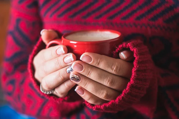 The girl in the red sweater holding a red cup of coffee