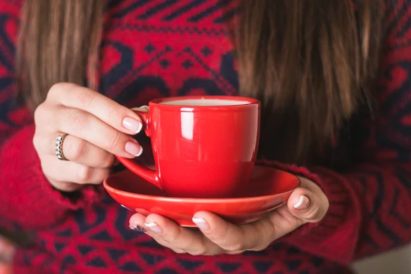 The girl in the red sweater holding a red cup of coffee