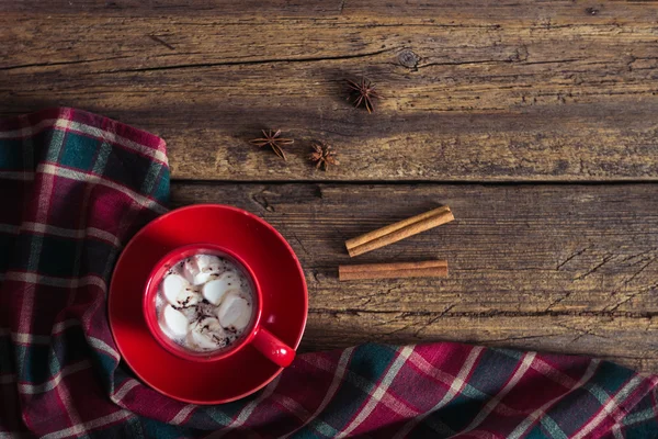 Red cup with cocoa and marshmallows on the wooden background