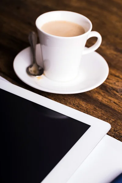 Digital tablet and coffee on old wooden background