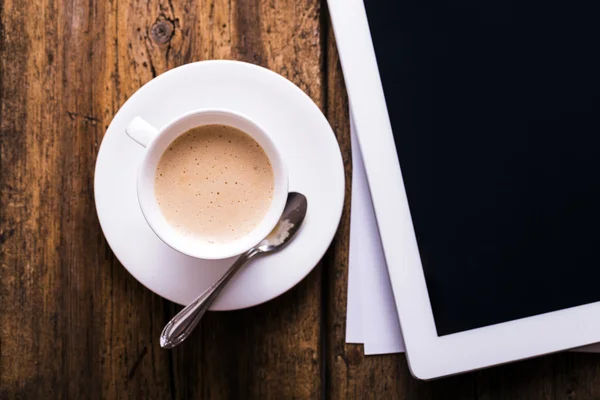 Digital tablet and coffee on old wooden background