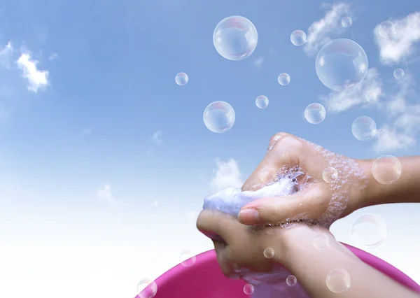 Female Hand washing clothes in the pink basin with clear Bubble