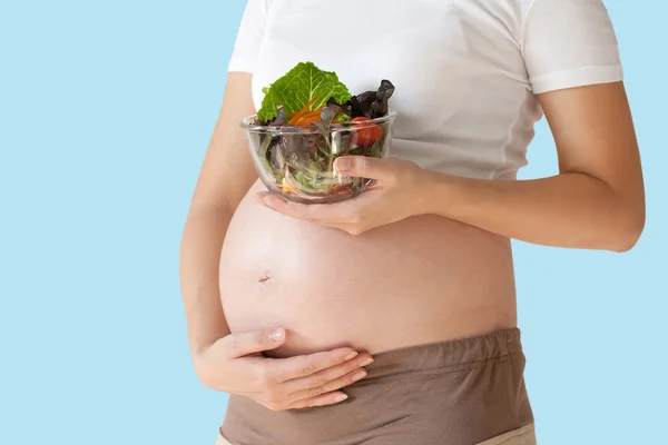 Pregnant woman\'s belly and vegetable salad